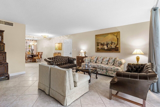 living area featuring a textured ceiling, visible vents, a chandelier, light tile patterned floors, and baseboards