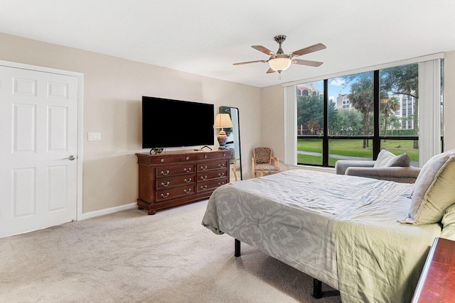 carpeted bedroom featuring ceiling fan and a wall of windows