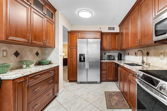 7129 Promenade Dr Unit 102, Boca Raton, FL 33433 - kitchen with light stone countertops, visible vents, a sink, decorative backsplash, and stainless steel appliances