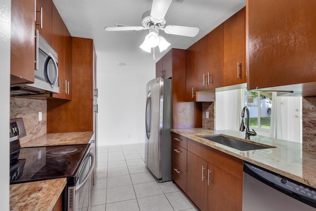 kitchen featuring sink, appliances with stainless steel finishes, light stone counters, light tile patterned flooring, and decorative backsplash