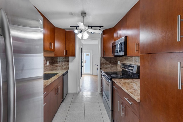 kitchen with light tile patterned floors, ceiling fan, stainless steel appliances, light stone counters, and decorative backsplash