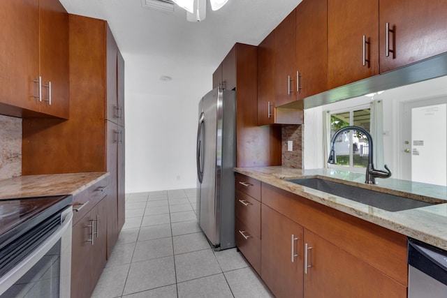 kitchen featuring sink, backsplash, light tile patterned floors, light stone counters, and stainless steel appliances