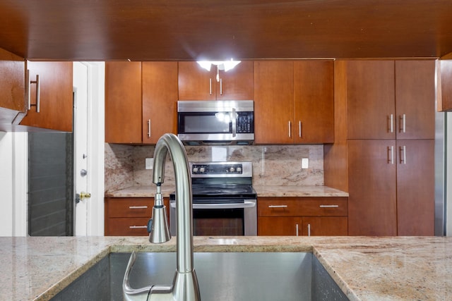 kitchen featuring light stone countertops, backsplash, and stainless steel appliances