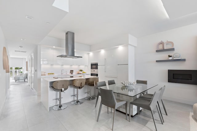 dining area with light tile patterned floors, a fireplace, and baseboards