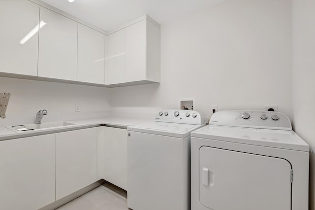 clothes washing area featuring cabinet space, a sink, and washer and clothes dryer