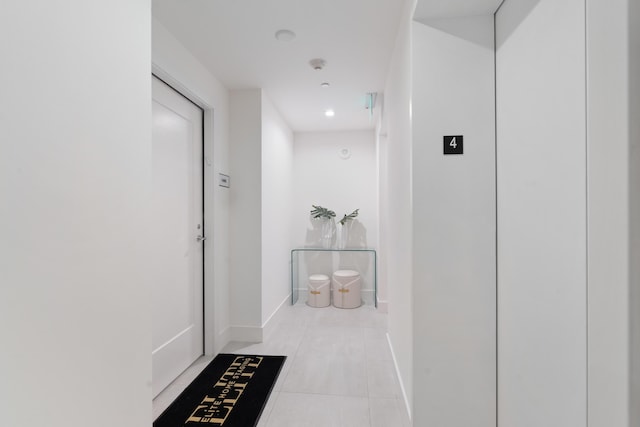 hallway featuring tile patterned flooring, elevator, and baseboards