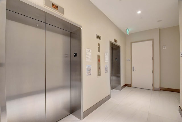 hallway with elevator and baseboards