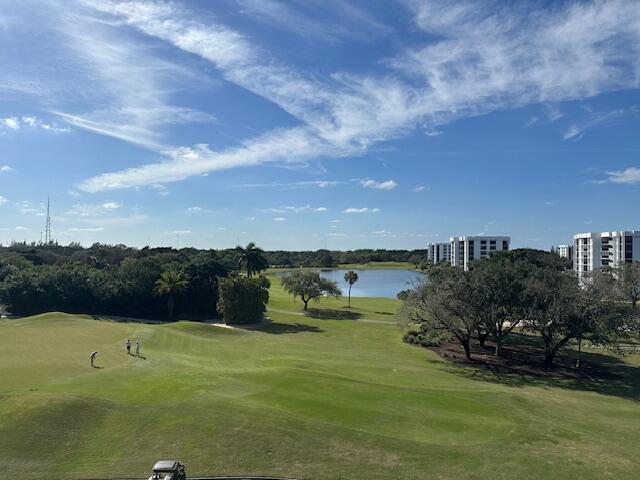 view of property's community featuring a water view, a lawn, and golf course view