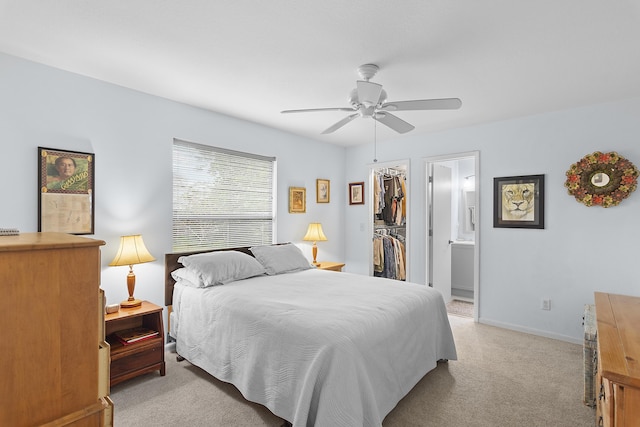 bedroom with a spacious closet, connected bathroom, light carpet, a closet, and ceiling fan