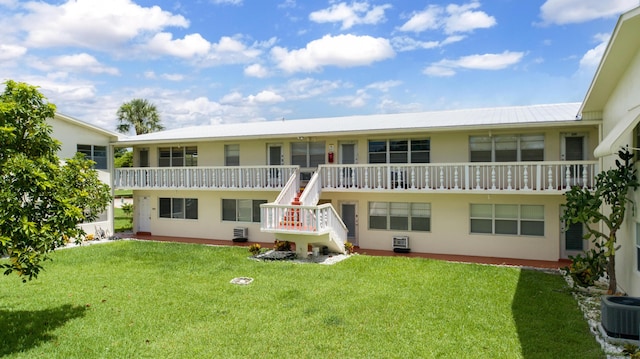 rear view of property featuring a lawn and central air condition unit