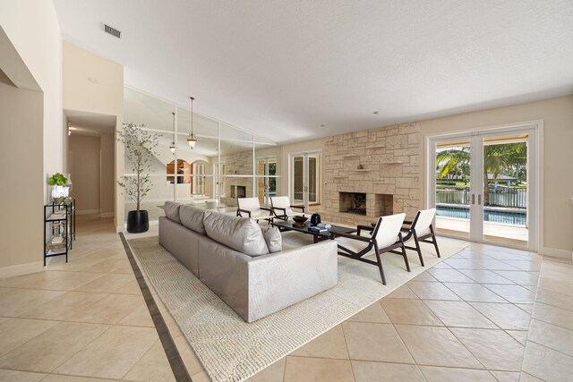 living room with a fireplace, vaulted ceiling, a textured ceiling, and light tile patterned floors