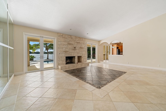 unfurnished living room featuring light tile patterned floors, a textured ceiling, a fireplace, and french doors