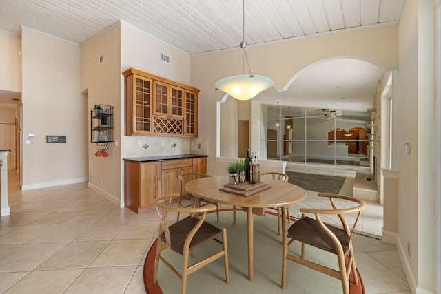 dining area featuring bar, light tile patterned floors, and wooden ceiling