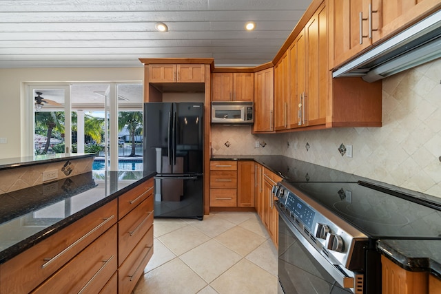 kitchen featuring tasteful backsplash, stainless steel appliances, light tile patterned floors, and dark stone counters