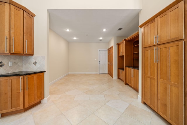 kitchen with light tile patterned floors, decorative backsplash, and dark stone counters