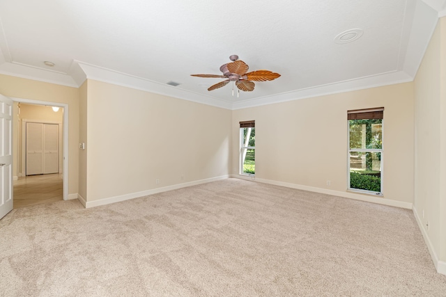 carpeted empty room with ceiling fan, ornamental molding, and plenty of natural light