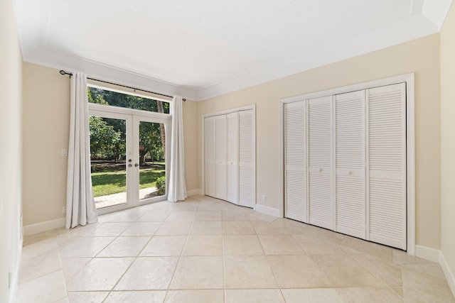 unfurnished bedroom with light tile patterned floors, ornamental molding, two closets, access to outside, and french doors