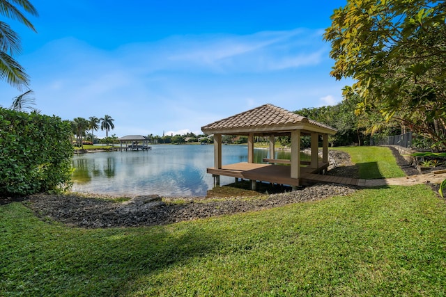 dock area with a water view, a gazebo, and a lawn