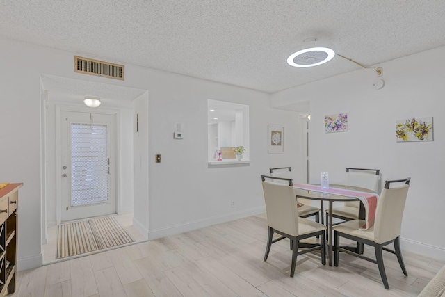 dining area with light hardwood / wood-style floors and a textured ceiling