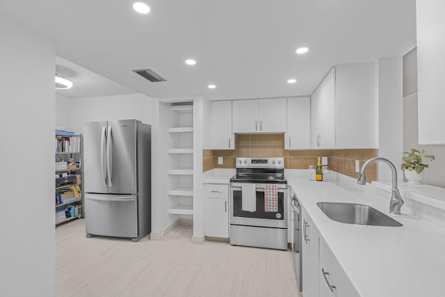 kitchen with tasteful backsplash, sink, white cabinets, and appliances with stainless steel finishes