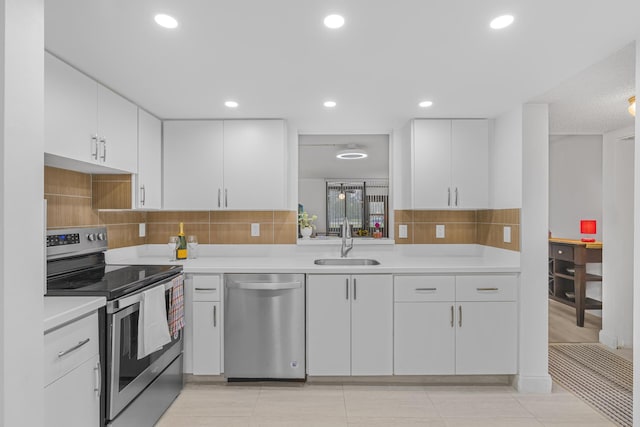 kitchen with light tile patterned flooring, sink, appliances with stainless steel finishes, white cabinets, and backsplash