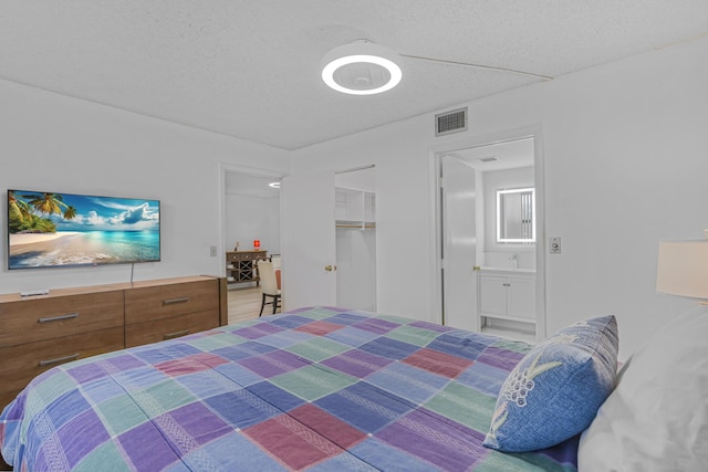 bedroom featuring a closet, ensuite bathroom, and a textured ceiling