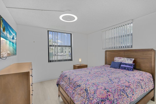 bedroom featuring a textured ceiling and light hardwood / wood-style flooring