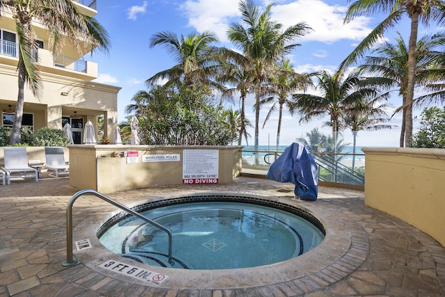 view of swimming pool with a patio, a water view, and a hot tub