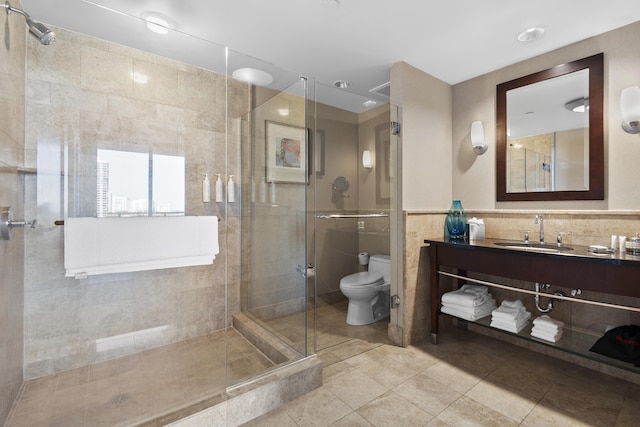 bathroom with an enclosed shower, tile patterned floors, tile walls, toilet, and vanity