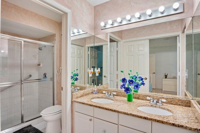 bathroom featuring vanity, toilet, and a shower with door