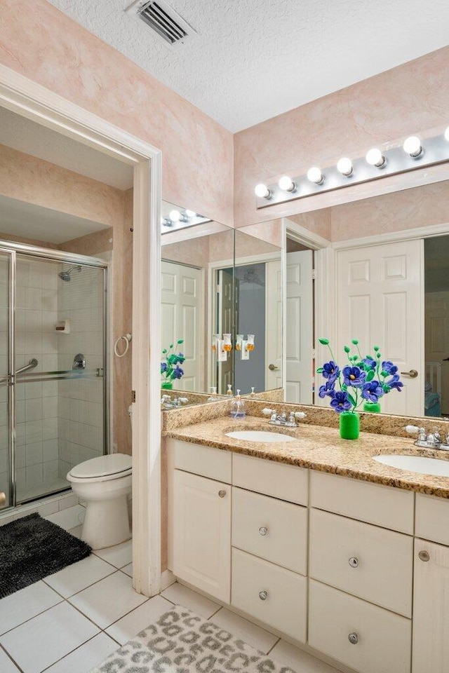 bathroom with tile patterned flooring, vanity, toilet, and a shower with shower door