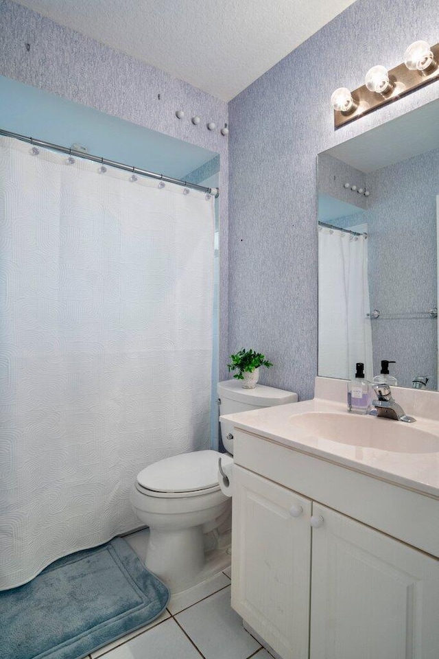 bathroom featuring tile patterned flooring, vanity, a textured ceiling, and toilet