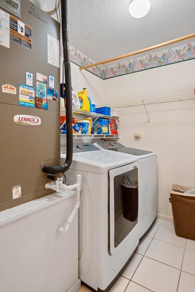 laundry room with light tile patterned flooring, heating unit, a textured ceiling, and washer and clothes dryer