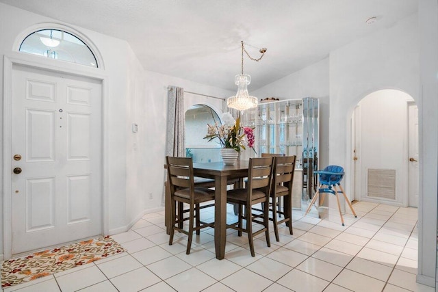 dining room with an inviting chandelier, vaulted ceiling, and light tile patterned floors