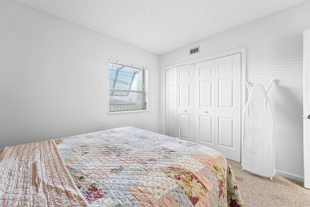 carpeted bedroom with a textured ceiling and a closet