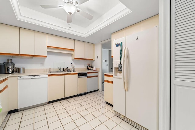 kitchen featuring white appliances, sink, a raised ceiling, ceiling fan, and cream cabinetry