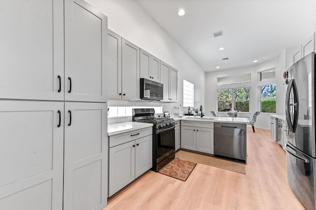 kitchen with sink, gray cabinetry, plenty of natural light, appliances with stainless steel finishes, and light hardwood / wood-style floors