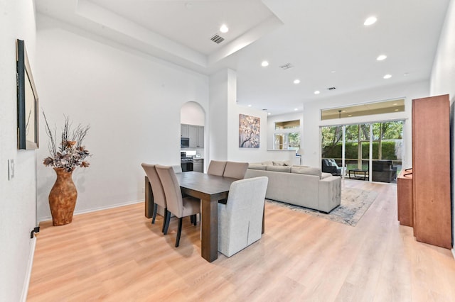 dining area with a tray ceiling and light hardwood / wood-style floors