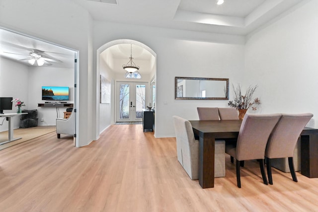 dining room featuring light hardwood / wood-style floors, french doors, and a raised ceiling