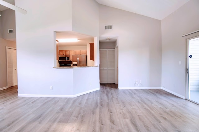 unfurnished living room with high vaulted ceiling and light hardwood / wood-style flooring