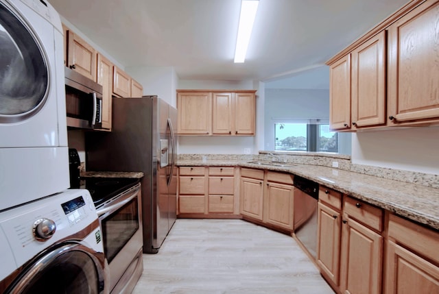 kitchen with light brown cabinetry, sink, light wood-type flooring, stacked washer / dryer, and stainless steel appliances