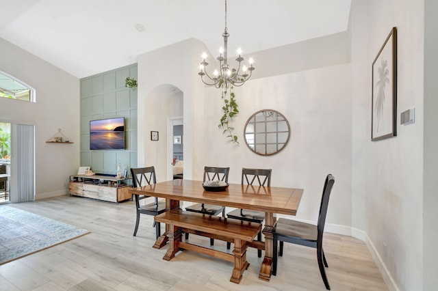 dining room featuring a towering ceiling, an inviting chandelier, and light hardwood / wood-style floors