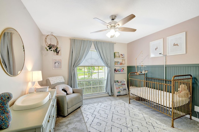 bedroom with light carpet, a crib, and ceiling fan