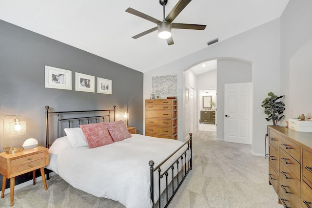 carpeted bedroom featuring vaulted ceiling, ceiling fan, and ensuite bath