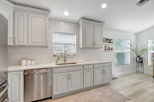 kitchen featuring sink, white cabinetry, tasteful backsplash, light wood-type flooring, and stainless steel appliances