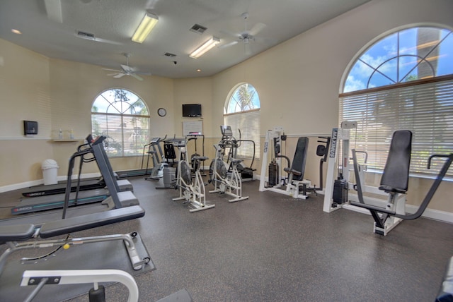 gym with a textured ceiling, a wealth of natural light, and ceiling fan