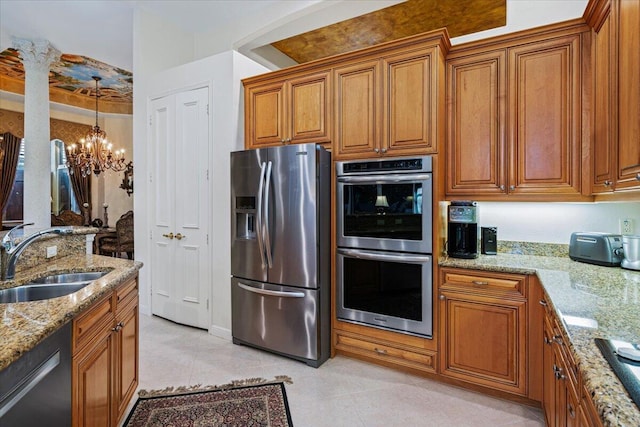 kitchen featuring pendant lighting, sink, appliances with stainless steel finishes, a notable chandelier, and light stone countertops