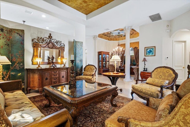 living area featuring decorative columns, tile patterned flooring, and an inviting chandelier