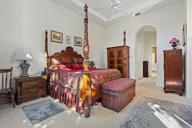 bedroom with light colored carpet, ceiling fan, and a tray ceiling