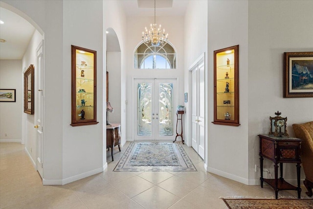 tiled foyer entrance with french doors, a notable chandelier, and a high ceiling